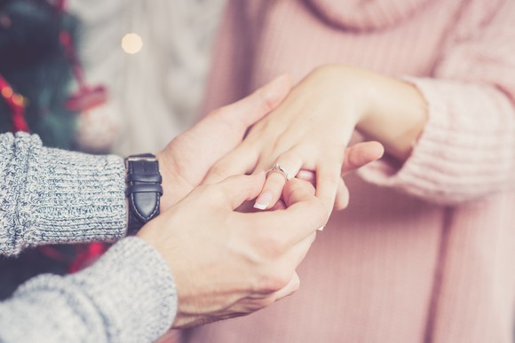 A man slips a ring on a woman's finger.