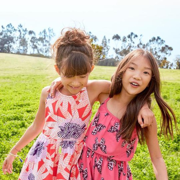 Two girls playing in a field wearing Gymboree dresses.