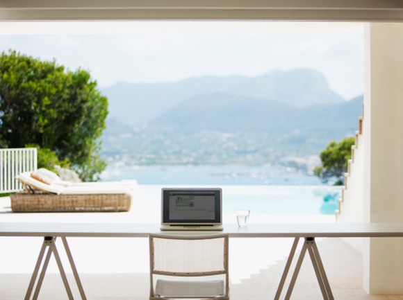 A laptop on a table with a background view of a waterfront