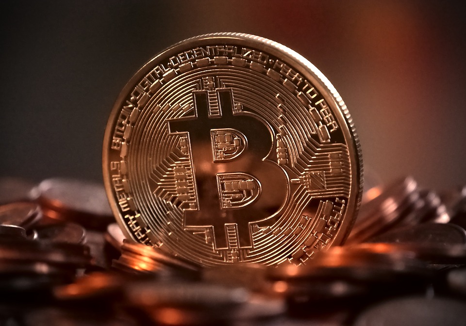 A physical bitcoin sitting atop a sea of other bitcoins.
