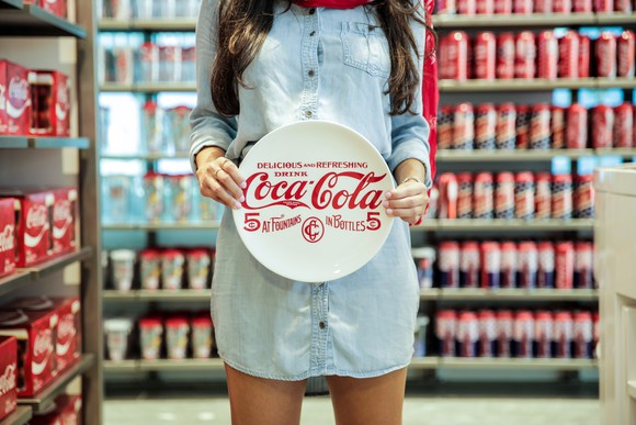A woman holds a plate with the Coca-Cola logo.