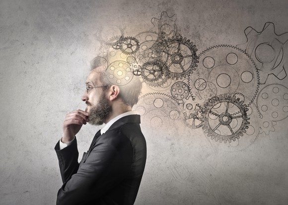 A man thinking with images of turning wheels coming out of his head.