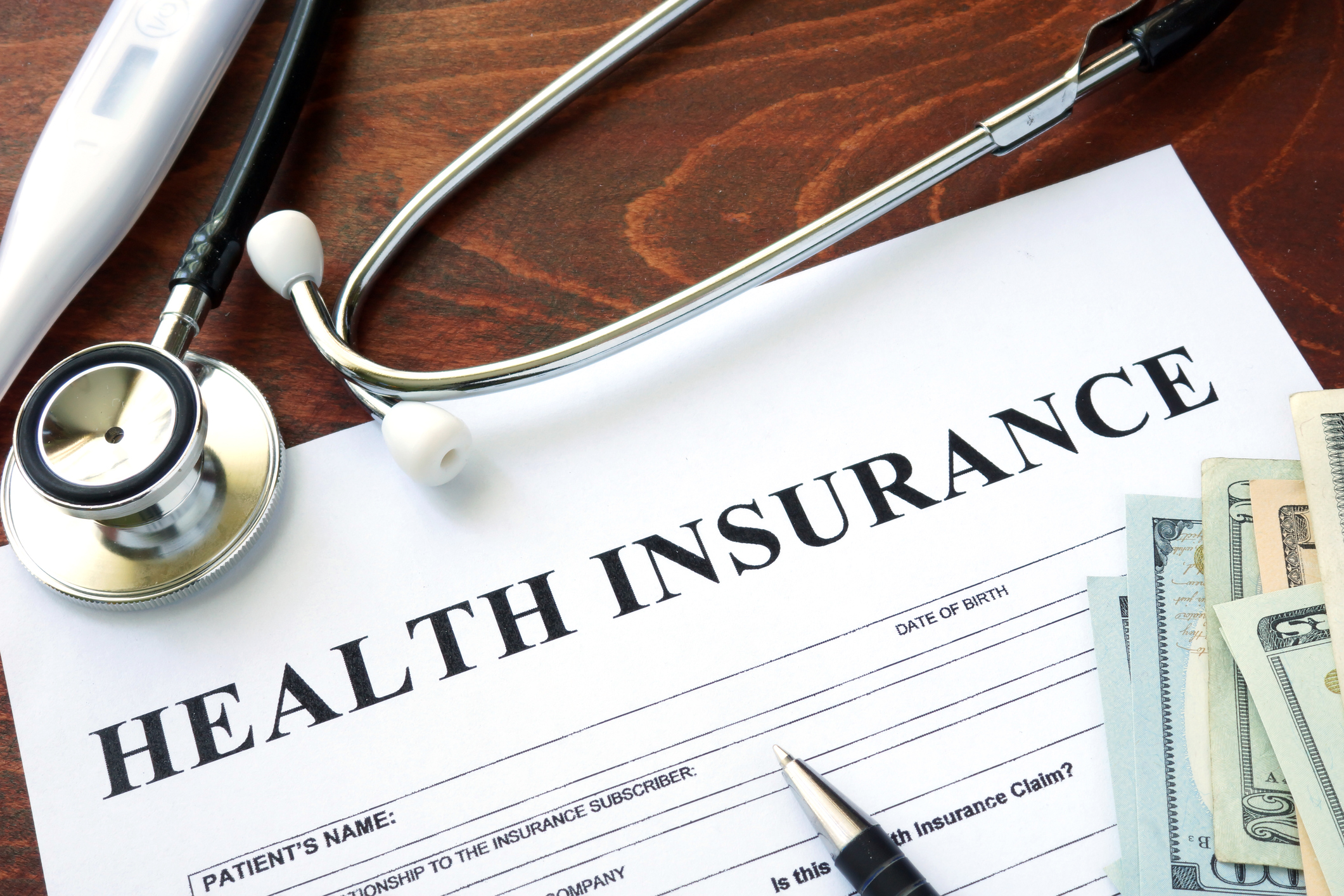 Top of health insurance form, with stethoscope and some cash