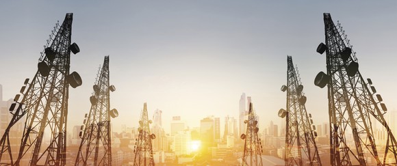 Wireless telecom towers sit in front of a rising sun