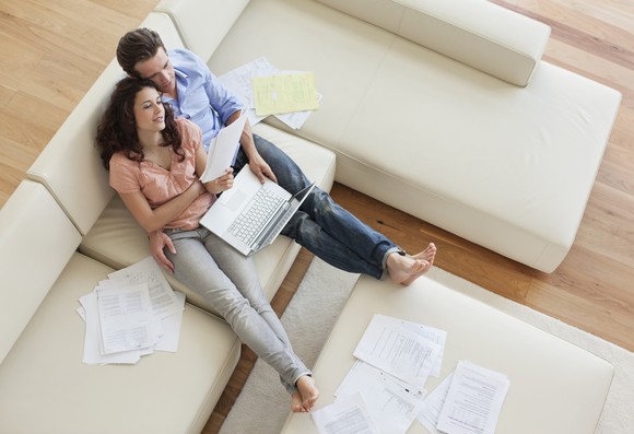 Couple on sofa looking at documents and PC