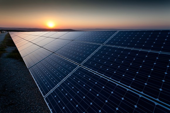 Utility scale solar farm with a setting sun in the background.