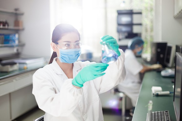 Pharmaceutical laboratory scientist examining a flask. 