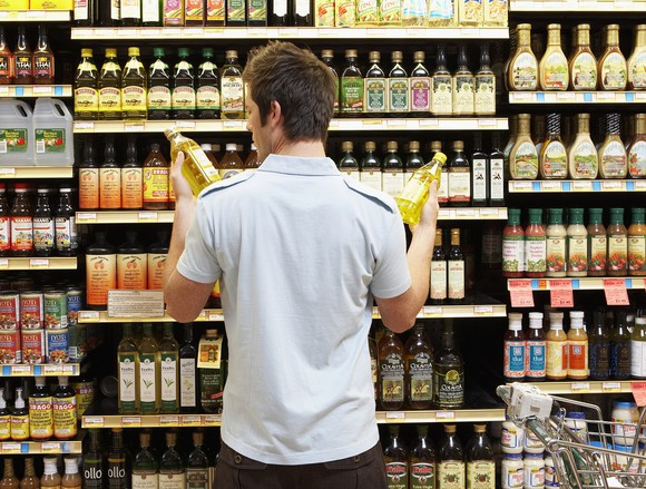 A young shopper in a grocery store compares two similar products.