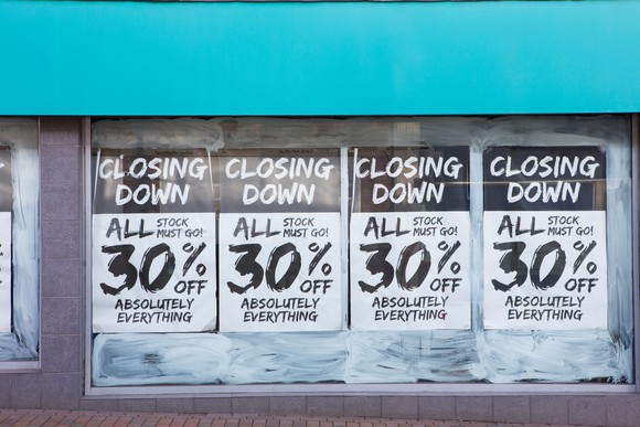 Retail storefront with going-out-of-business posters in window.