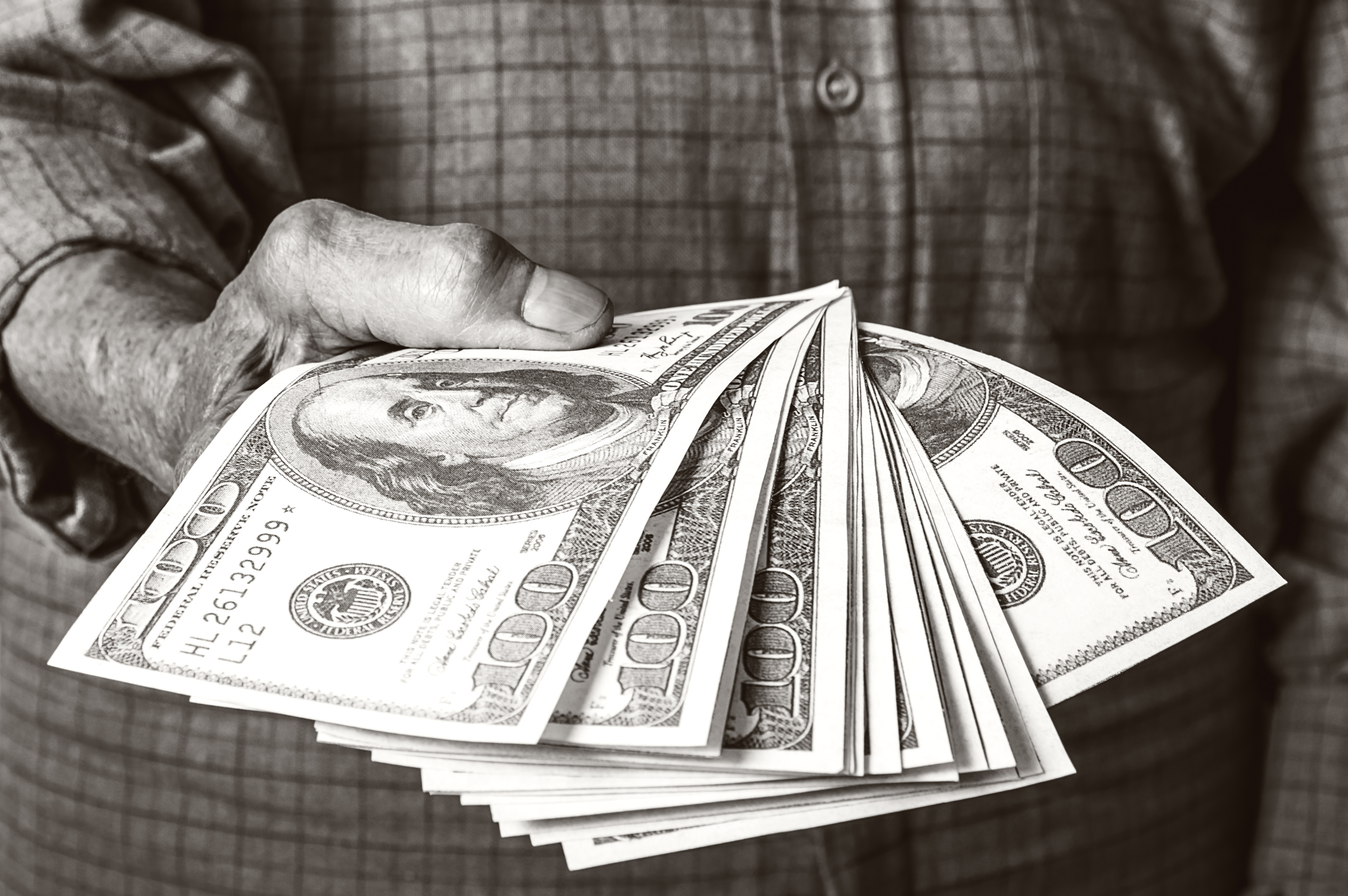 A senior holding a stack of Social Security cash.