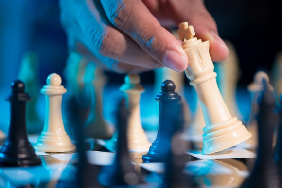 A hand moving the king in a chess game.