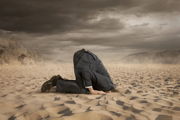 A businessman with his head in the sand, a not-so-good response to a crisis.