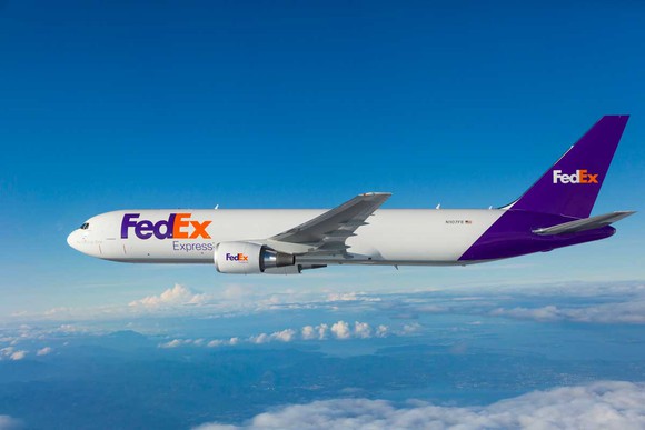 A FedEx Boeing 767 aircraft flying above the clouds.
