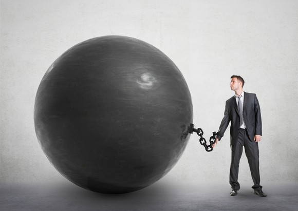 A man in a suit, chained to giant black ball.
