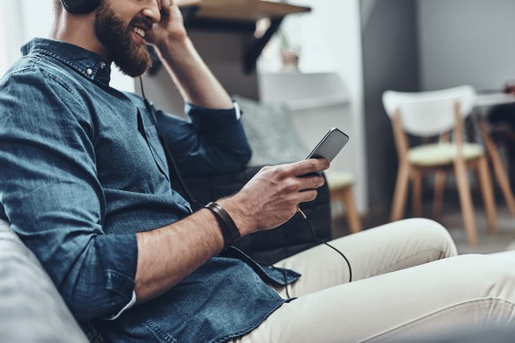 Man sitting on couch listening to music on his phone