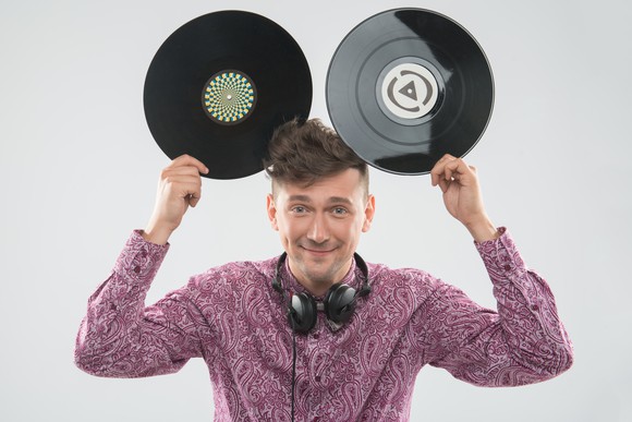 excited young DJ with stylish haircut, bow tie having fun with vinyl records - holding two up to his head like Mickey Mouse ears excited young DJ with stylish haircut, bow tie having fun with vinyl records - holding two up to his head like Mickey Mouse ears
