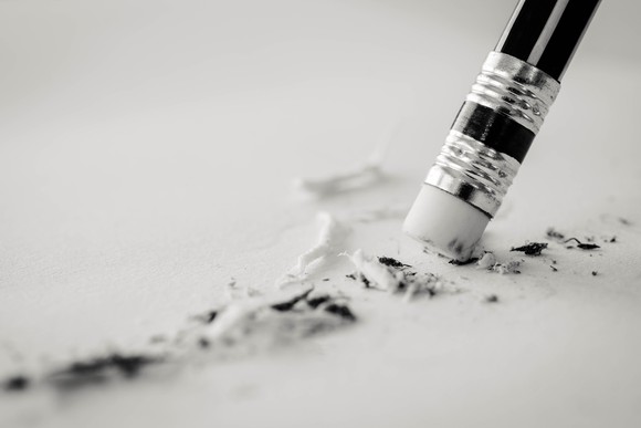 pencil eraser removing a written mistake on a piece of paper