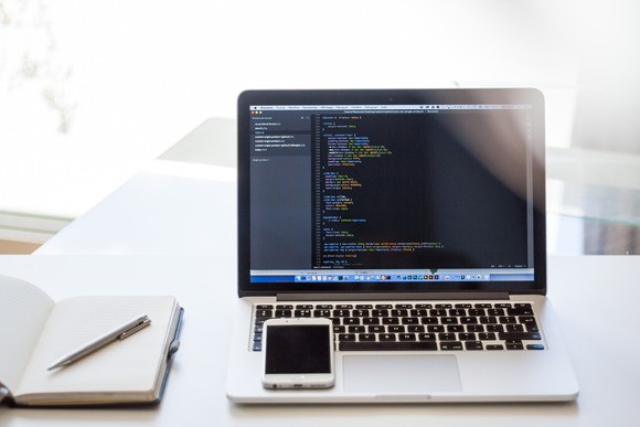 A smartphone and a laptop with code on the screen.