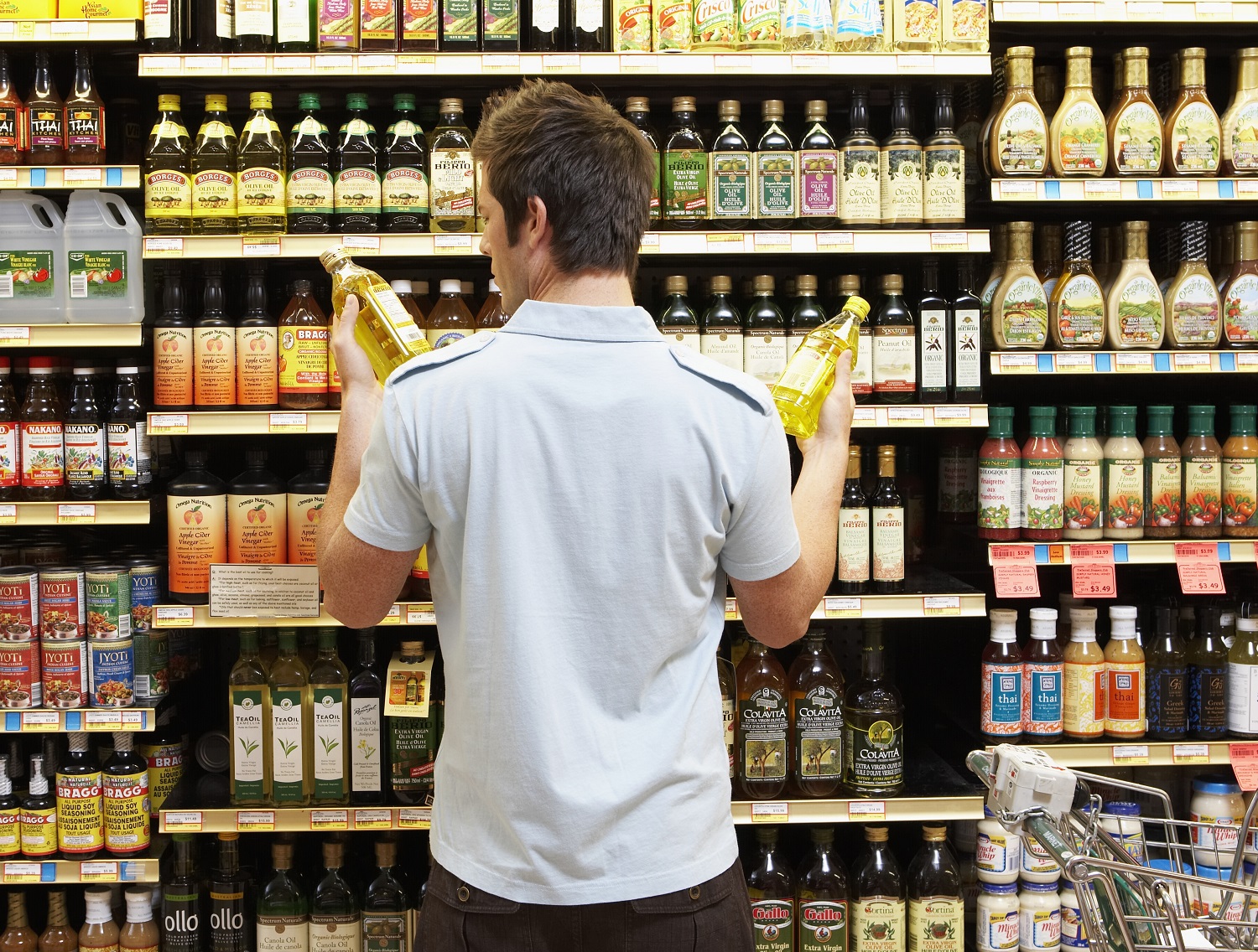 A young shopper compares two products in grocery aisle.