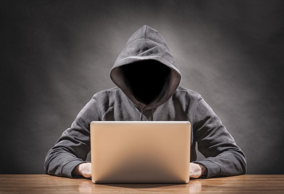Faceless hoodie working on laptop