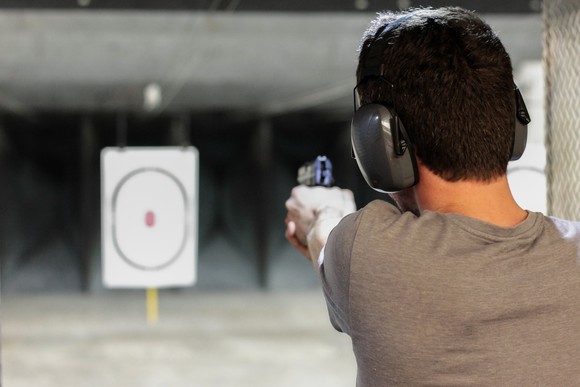 A man at a shooting range aiming at a target.