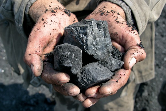 Miner holding lumps of coal.