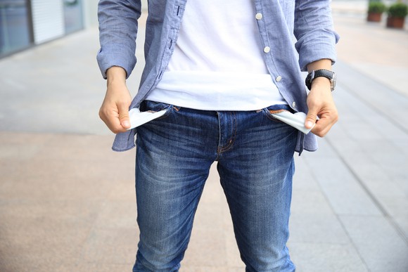 A man pulling out his pant pockets and exposing a lack of money.