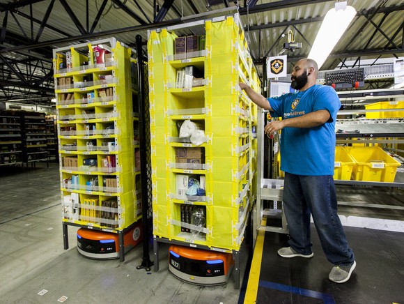 A worker and a robot in an Amazon warehouse