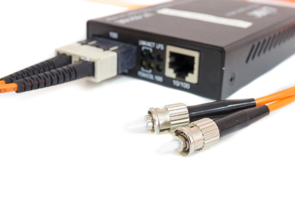 Fiber-optic cables connected to transceivers in an Ethernet media conversion box.