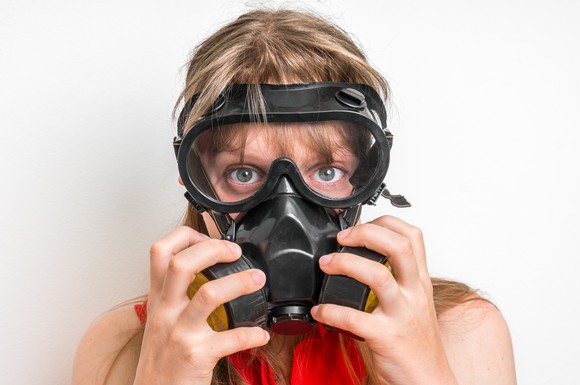 Young business woman with gas mask isolated on white.
