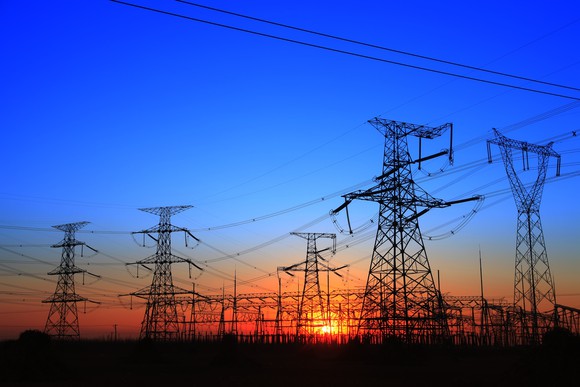 A cluster of transmission towers and power lines at sunset.