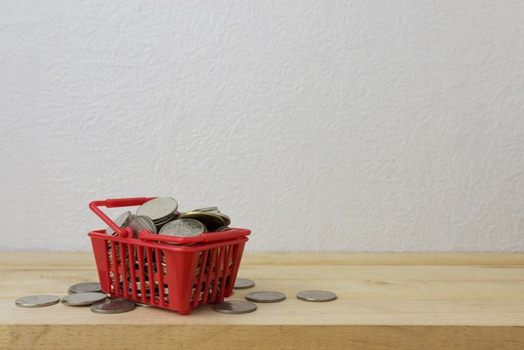 A red hand cart is filled to the top and overflowing with coins.