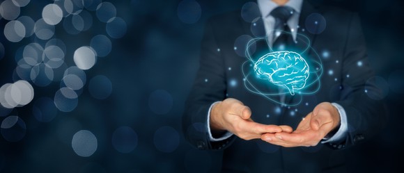 Businessman in suit holding electronic brain representing artificial intelligence.