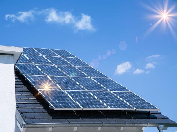 Solar panels on a residential roof with the sun in the background