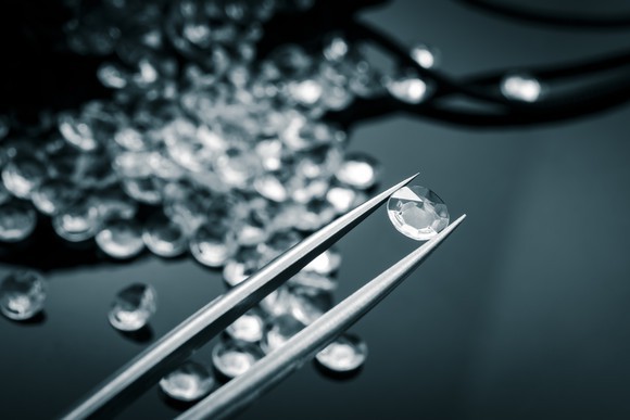 Examining a diamond in a pair of tweezers.