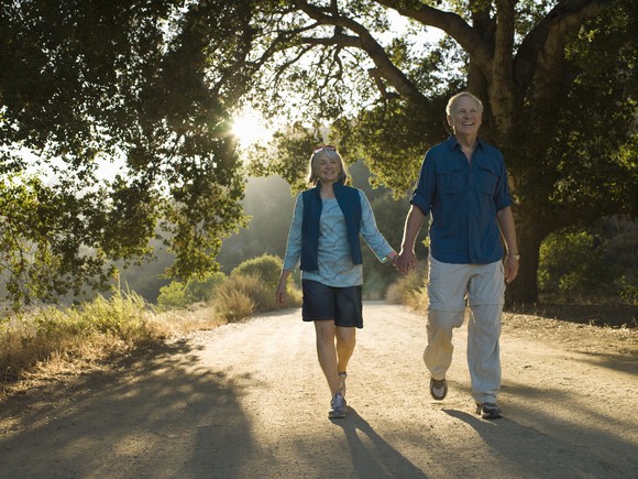 Retired couple holding hands while walking.