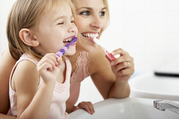 A mom and daughter brushing teeth.