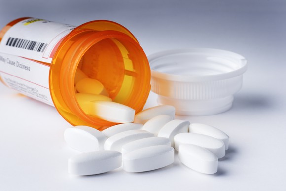Prescription pills falling out of a bottle.