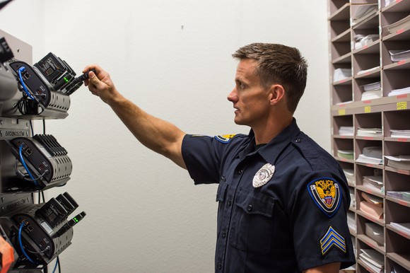 Police officer putting a body camera in a dock