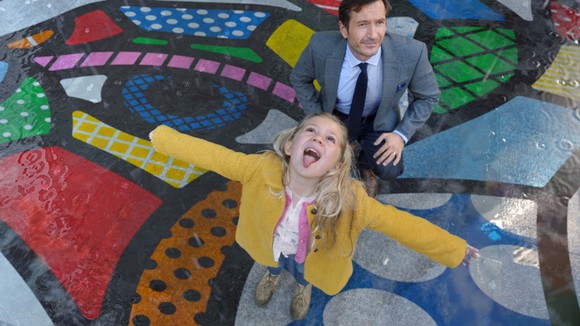 Young girl in colorful park opening her mouth to catch falling raindrops.