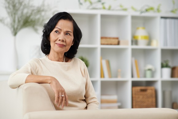 Senior woman sitting on couch and thinking