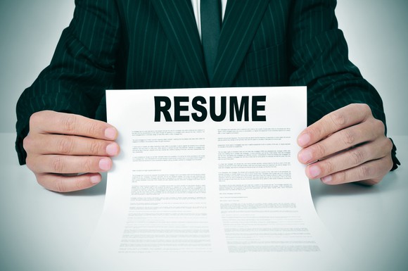 A man in a suit holding out a resume