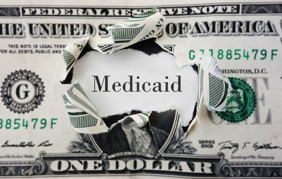 A $1 bill with Medicaid where George Washington's portrait usually is.