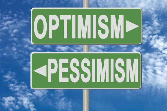 Green signs that say "optimism" and "pessimism."