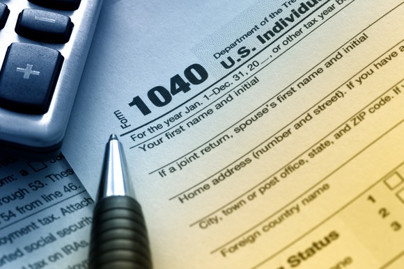 An IRS 1040 tax form next to a calculator and pen.