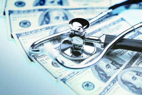 A stethoscope lying atop a pile of cash.