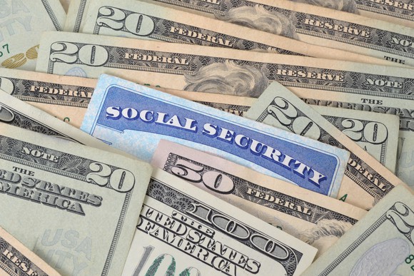 The top of a Social Security card peeks out from a pile of currency.