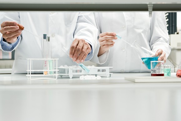 Two scientists work side by side with lab equipment in a clinic.