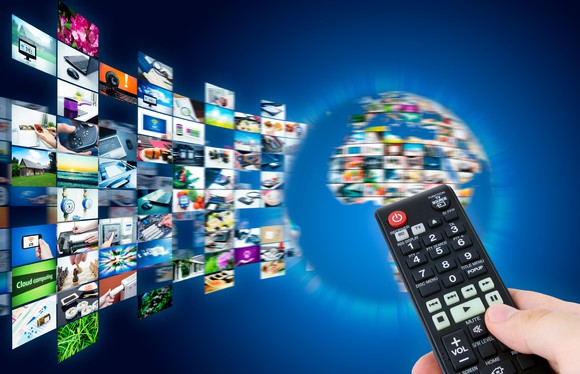 A person holding a television remote pointed at a variety of channels around the world.