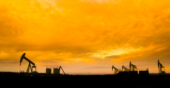 Silhouette of oil pumps at oil field with sunset sky background.